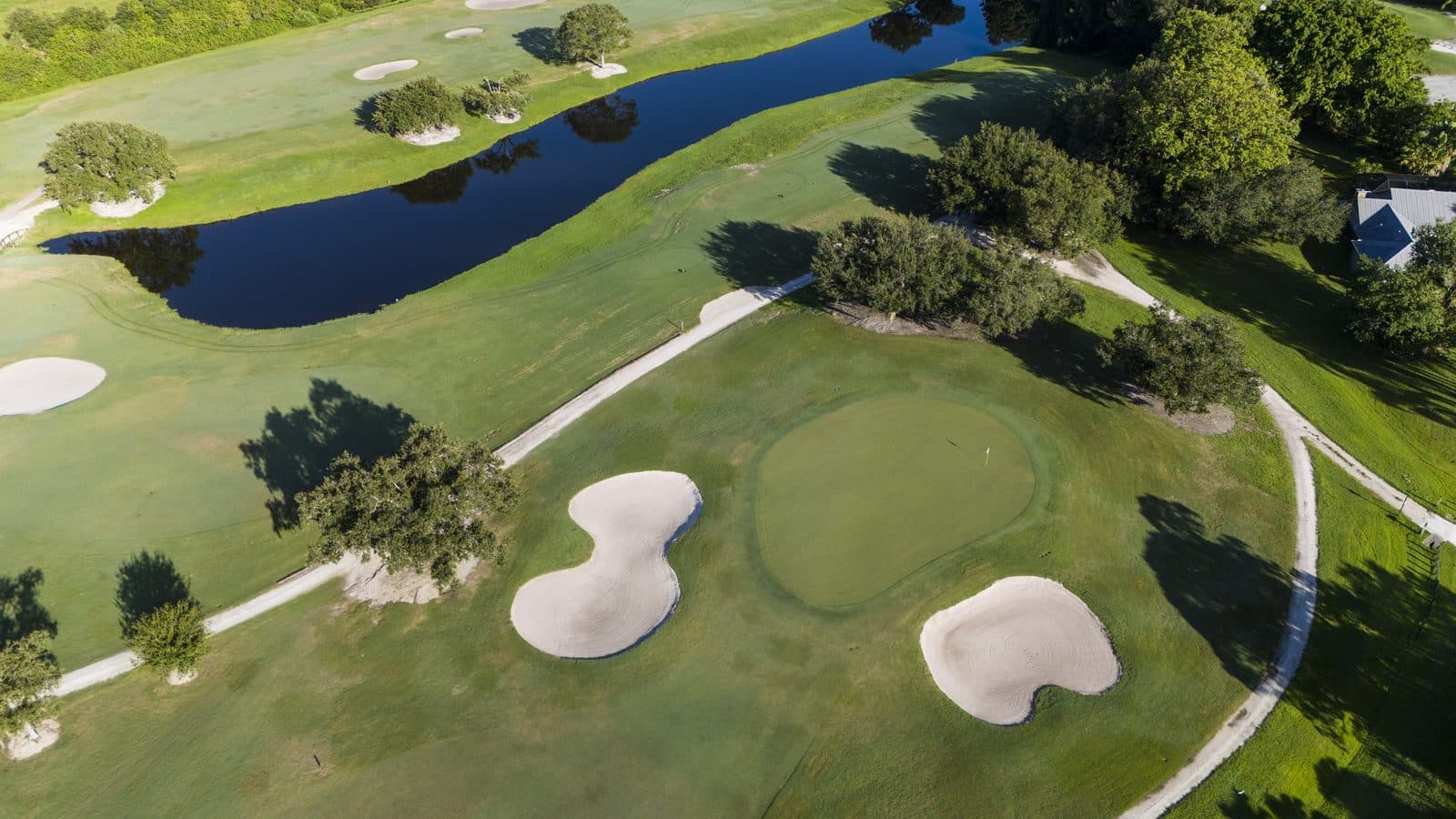 Aerial of a Banyan Creek green guarded by two bunkers, with a lake beyond