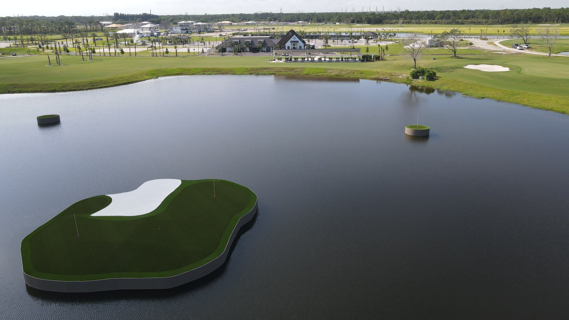 Aerial view of the Glynlea Country Club aquatic driving range with a floating target green, golf shop, and Wylder homes in Port St. Lucie