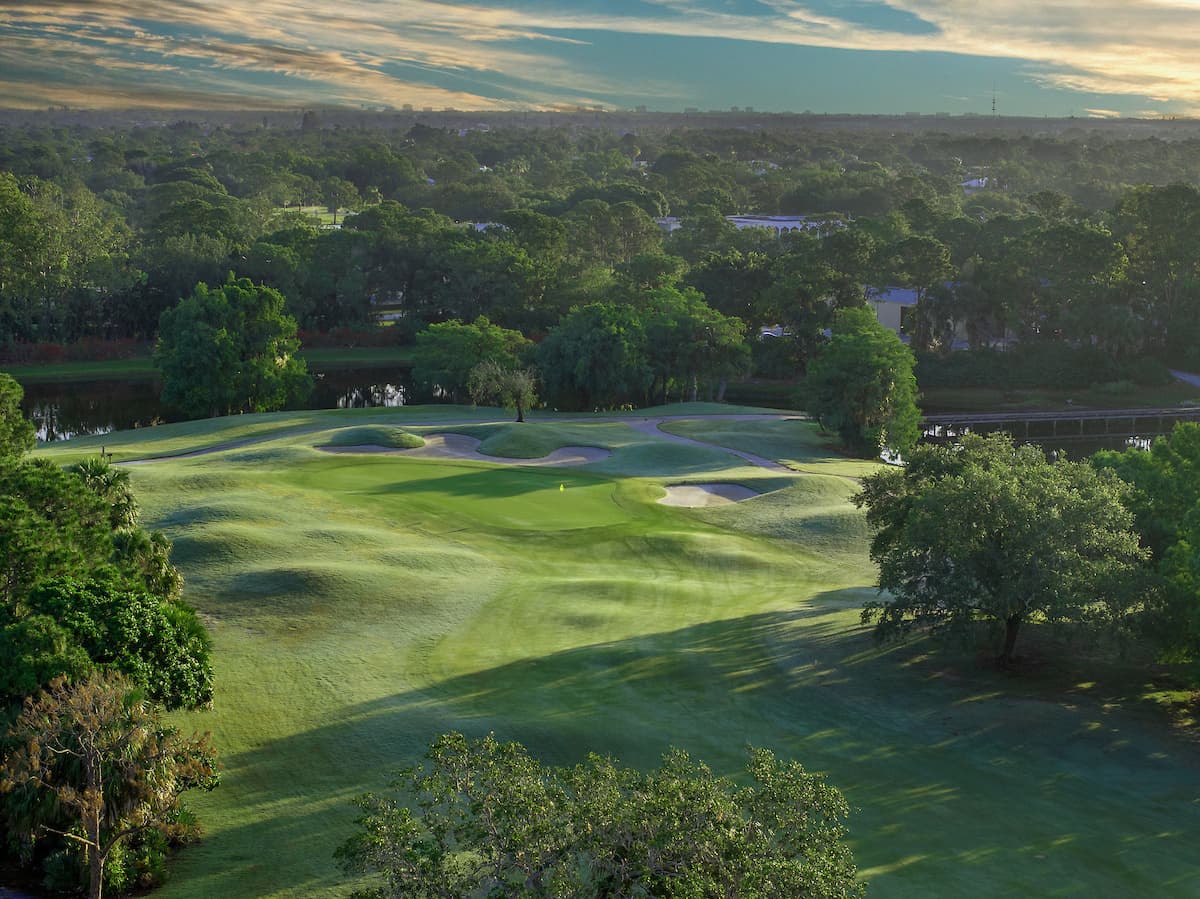 Aerial of a Monarch fairway with mounding, bunkers, and live oaks at sunset
